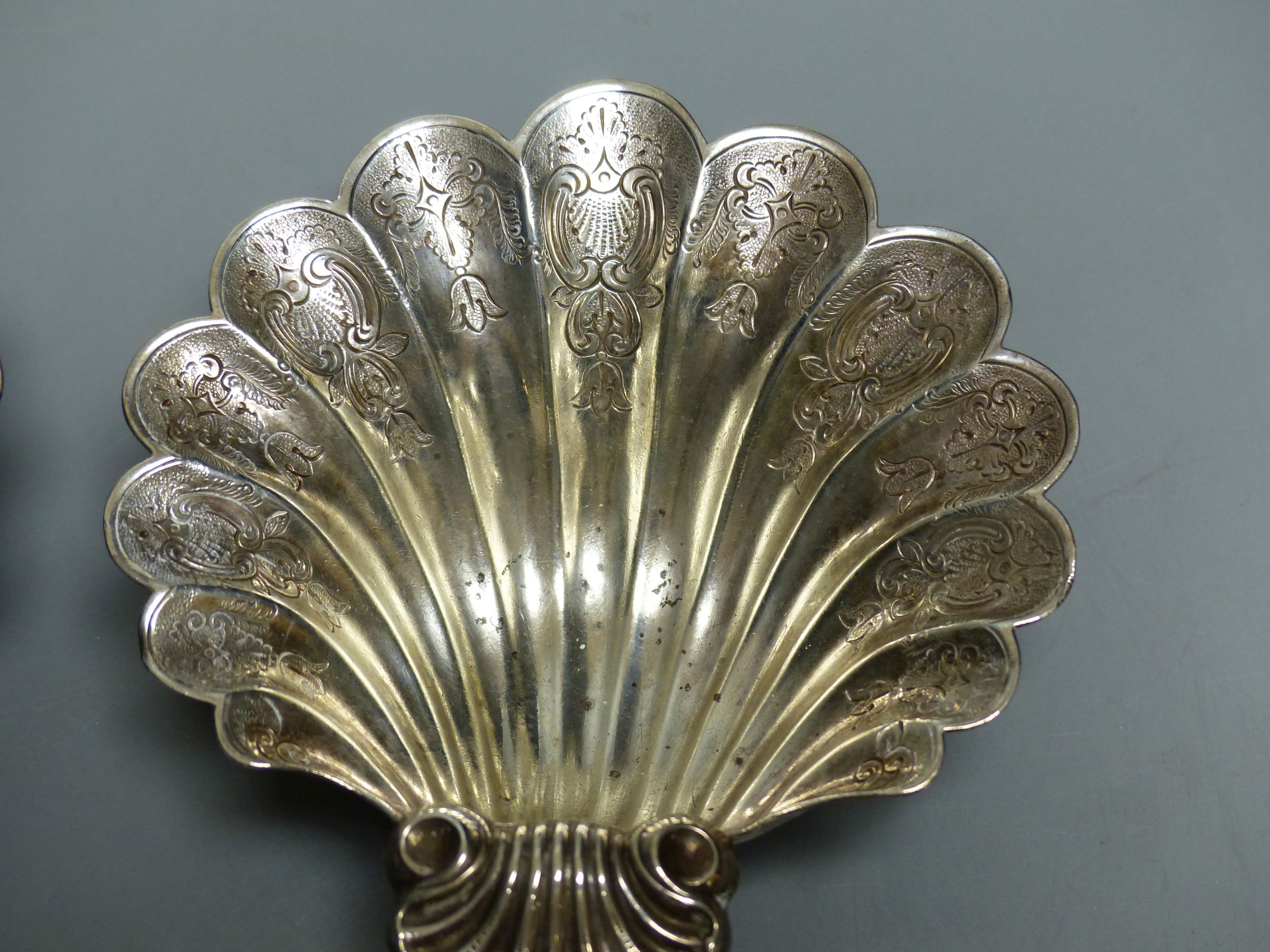 A pair of engraved scallop shell bon bon dishes on three scrolled feet, London 1934, 12.6cm, 9oz.